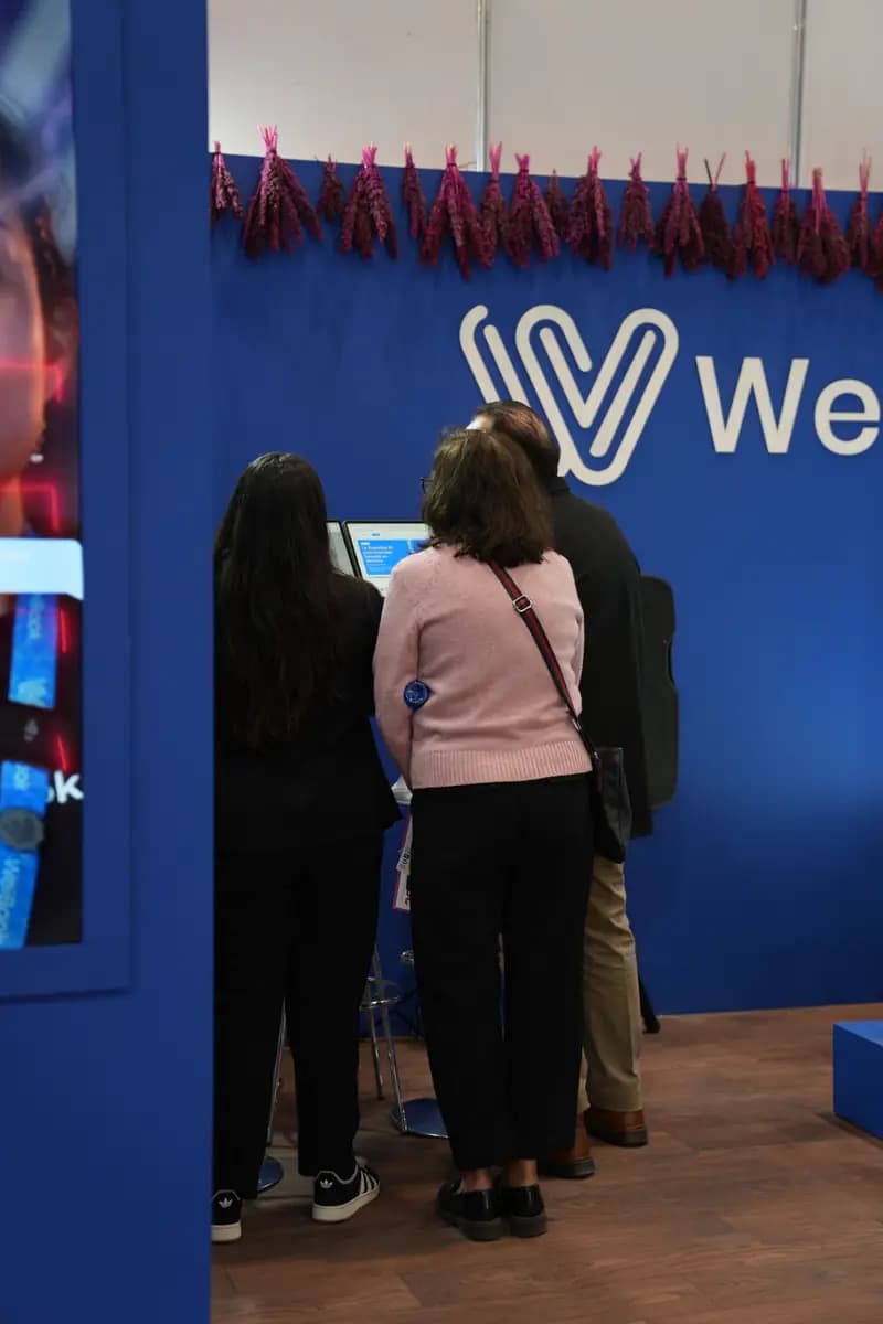 Visitantes reciben una demostración de WeiBook en un stand de México